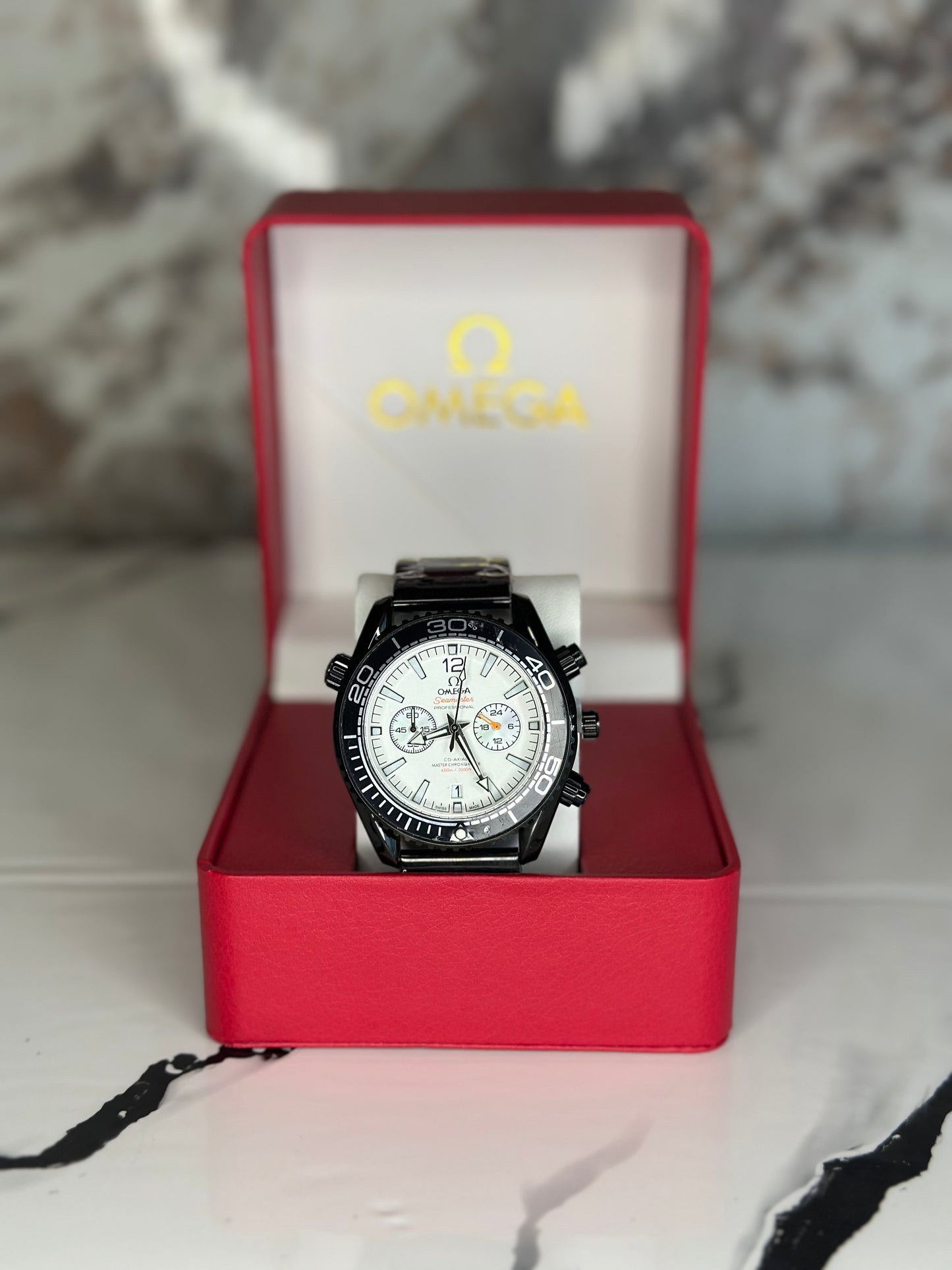 Reloj omega fondo blanco bisel negro pulsera metálica cronógrafo