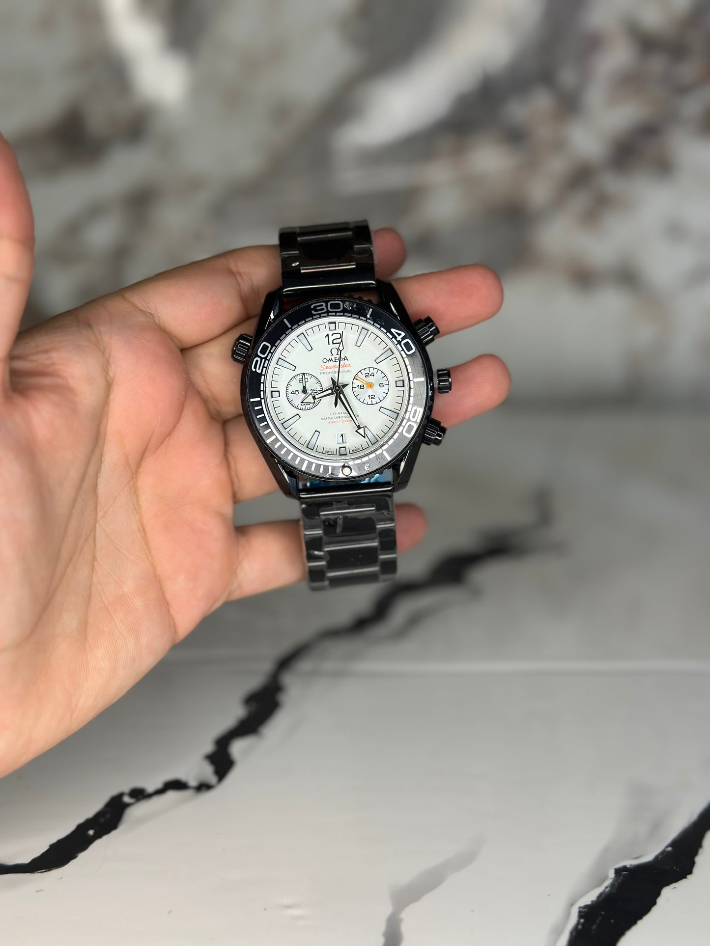 Reloj omega fondo blanco bisel negro pulsera metálica cronógrafo