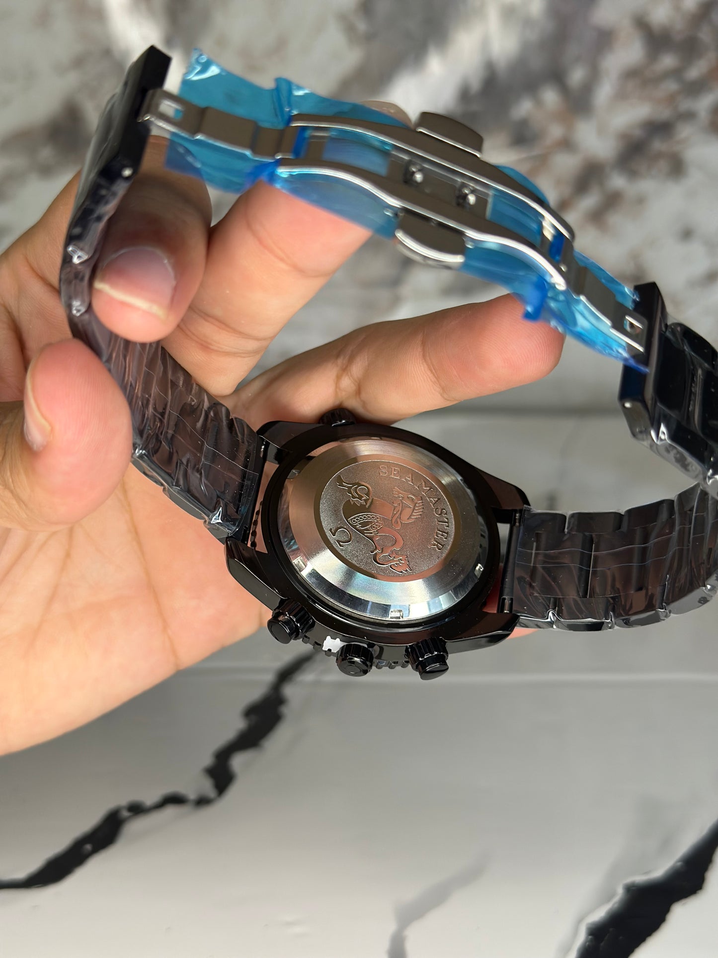 Reloj omega fondo blanco bisel negro pulsera metálica cronógrafo