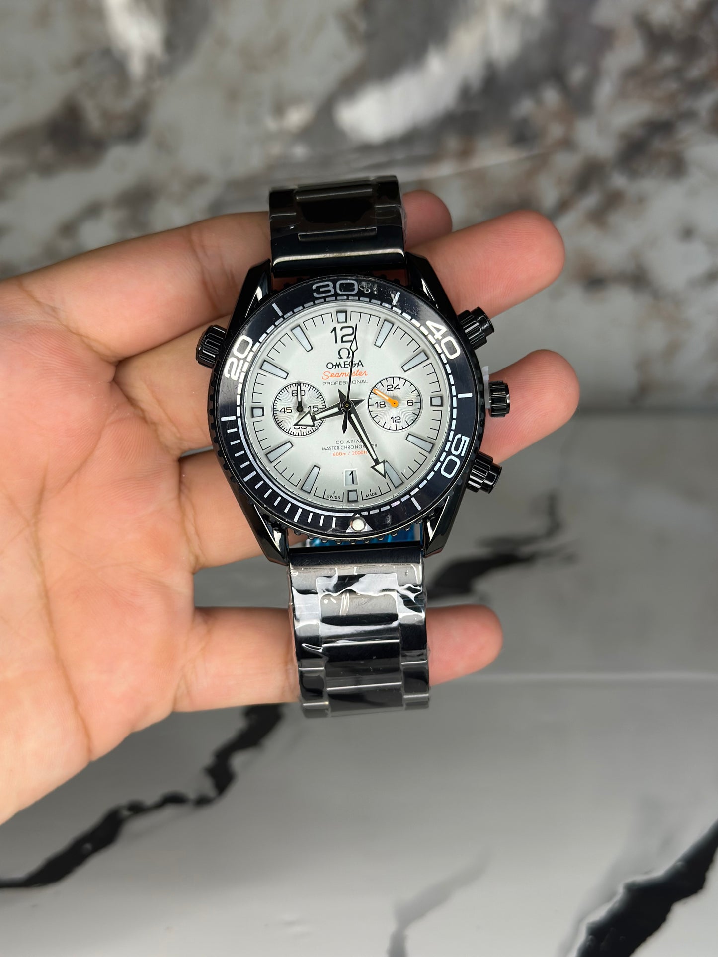 Reloj omega fondo blanco bisel negro pulsera metálica cronógrafo